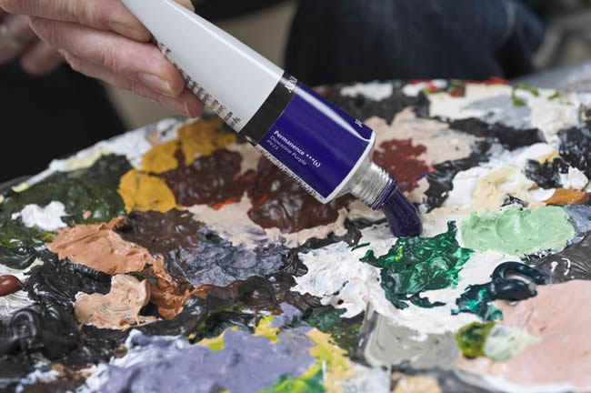 Artist squeezing acrylic paint onto palette