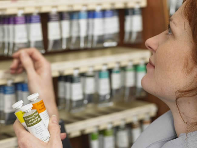 Woman selecting tubes of paint in art shop, profile