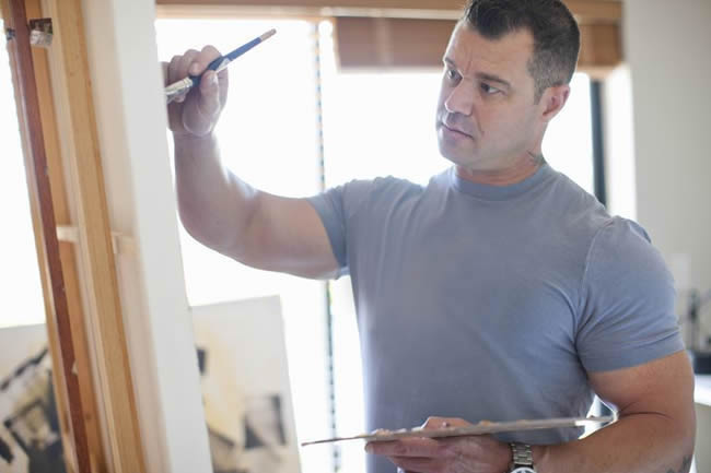 Male artist painting on an easel.