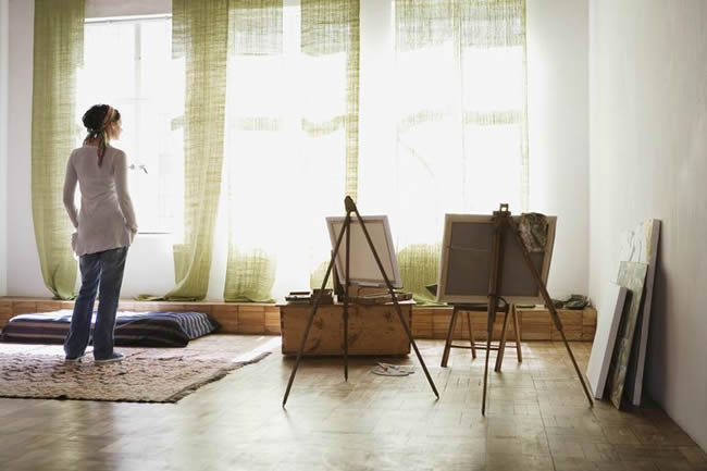 Woman standing in artist's studio, rear view