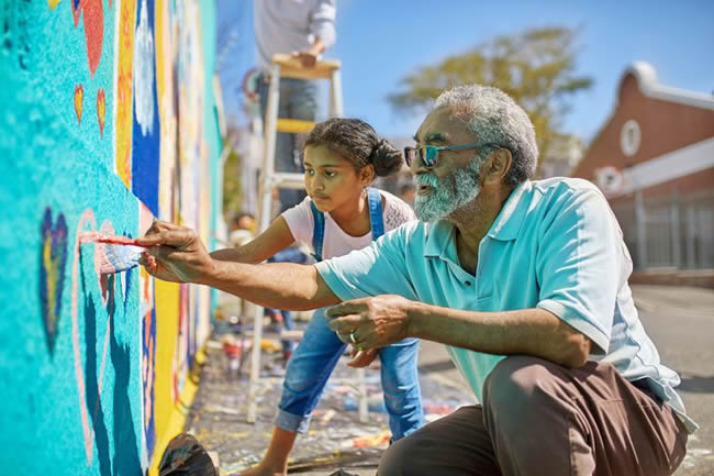 grandfather and granddaughter painting mural