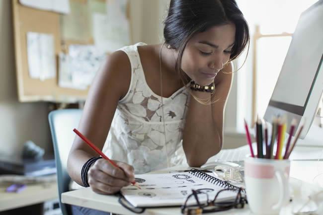 Young female artist drawing jewelry design in sketch book