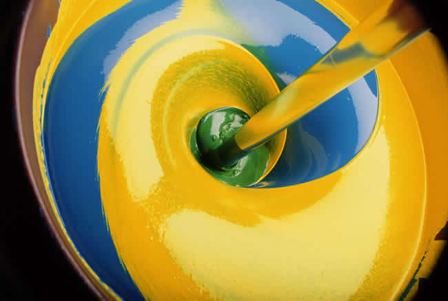 Swirl of yellow and blue paint producing green, close-up