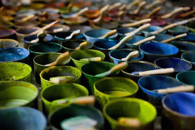 Colorful, small cans of paint with brushes in them