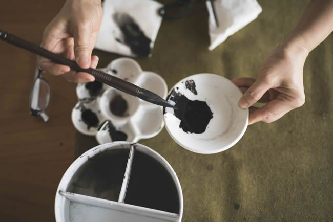 Hand holding writing brush and inking