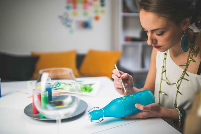 Woman painting design on glass bottle