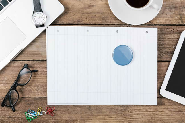 Paperweight On Blank Page Surrounded By Office Supplies On Table