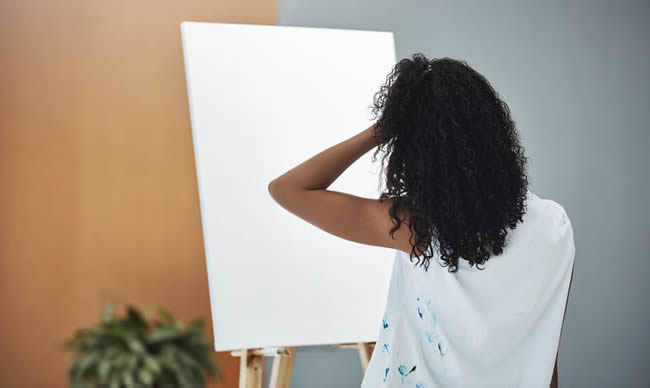 female painter looking at blank canvas