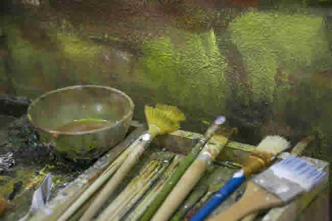 Brushes in front of an oil painting