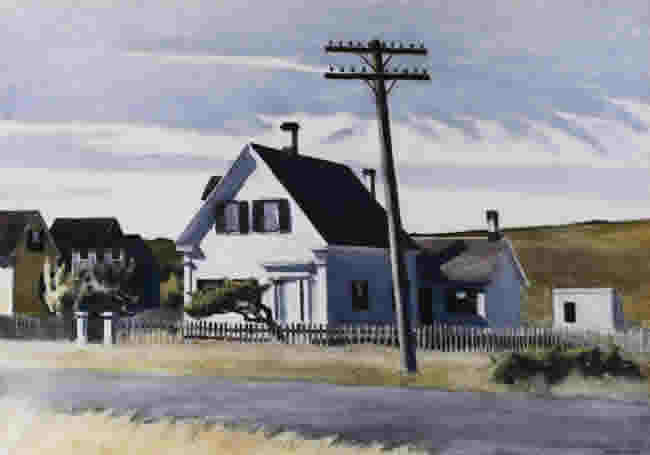 Small white house and lopsided telephone pole on a country road.