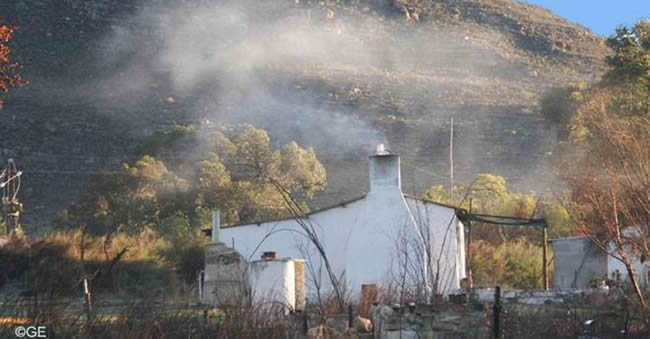 Cottage nestled against a rocky cliff.