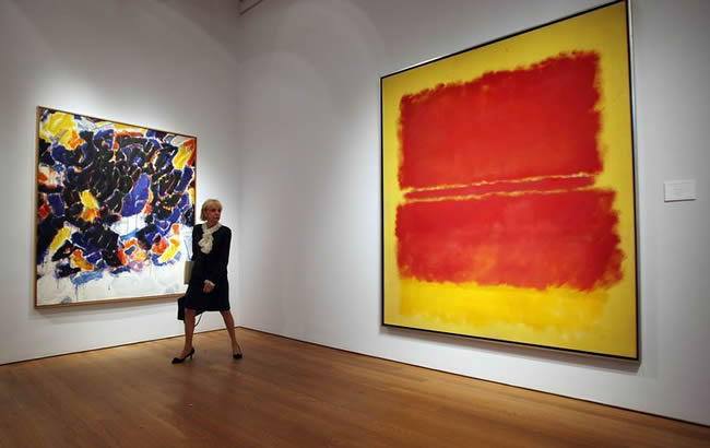 Woman looking at a red and yellow painting by Mark Rothko