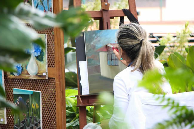 Woman painting on a canvas outside.