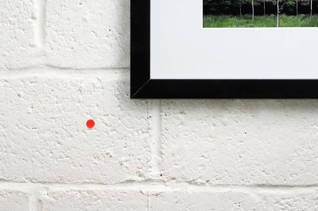 A small orange sticker beside a work of art indicates that is has been purchased