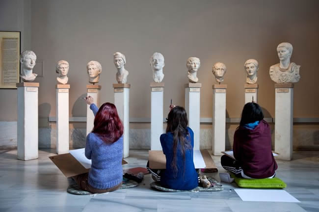 Students examining ancient sculptures.